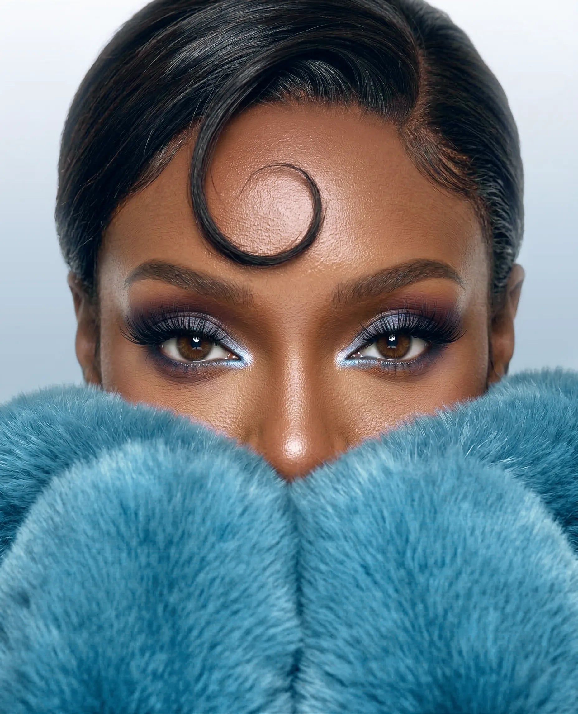 Woman wearing Studio Grade Inc.'s false lashes, blue eyeshadow and a fur coat.
