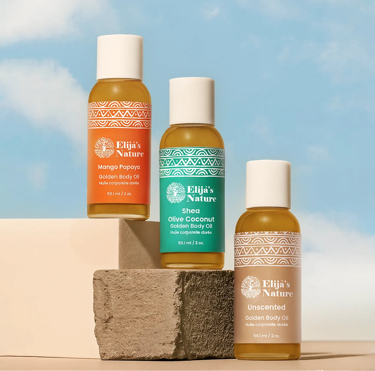 Heavenly Trio Gift Set - #size_2oz - Mini bottles of Elija’s Nature Mango Papaya, Olive Coconut, and Unscented body oils arranged on clay blocks against a bright blue sky
