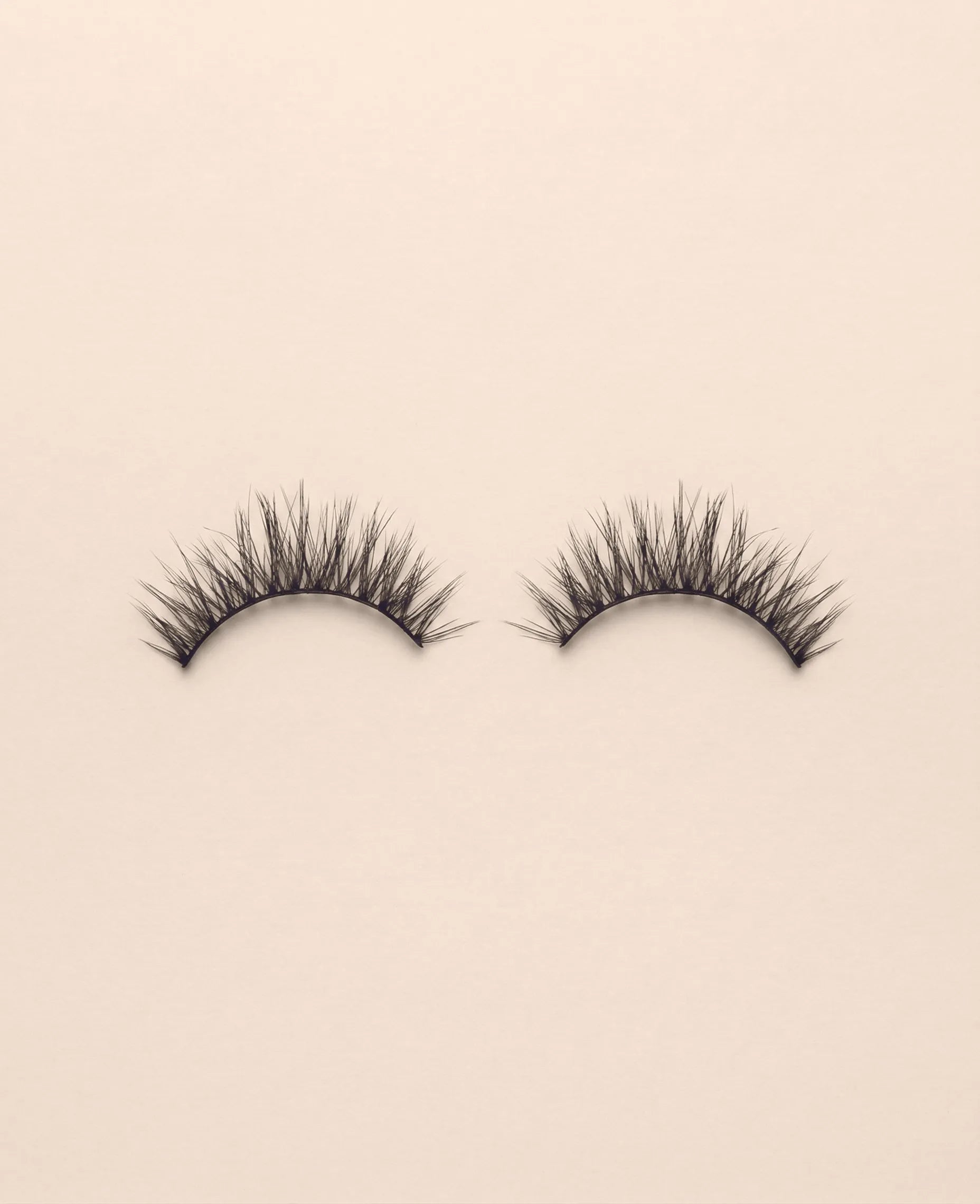 Pair of Lavish false eyelashes on a beige background.