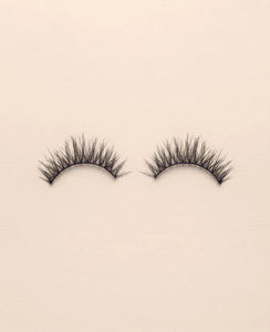 Pair of Lavish false eyelashes on a beige background.