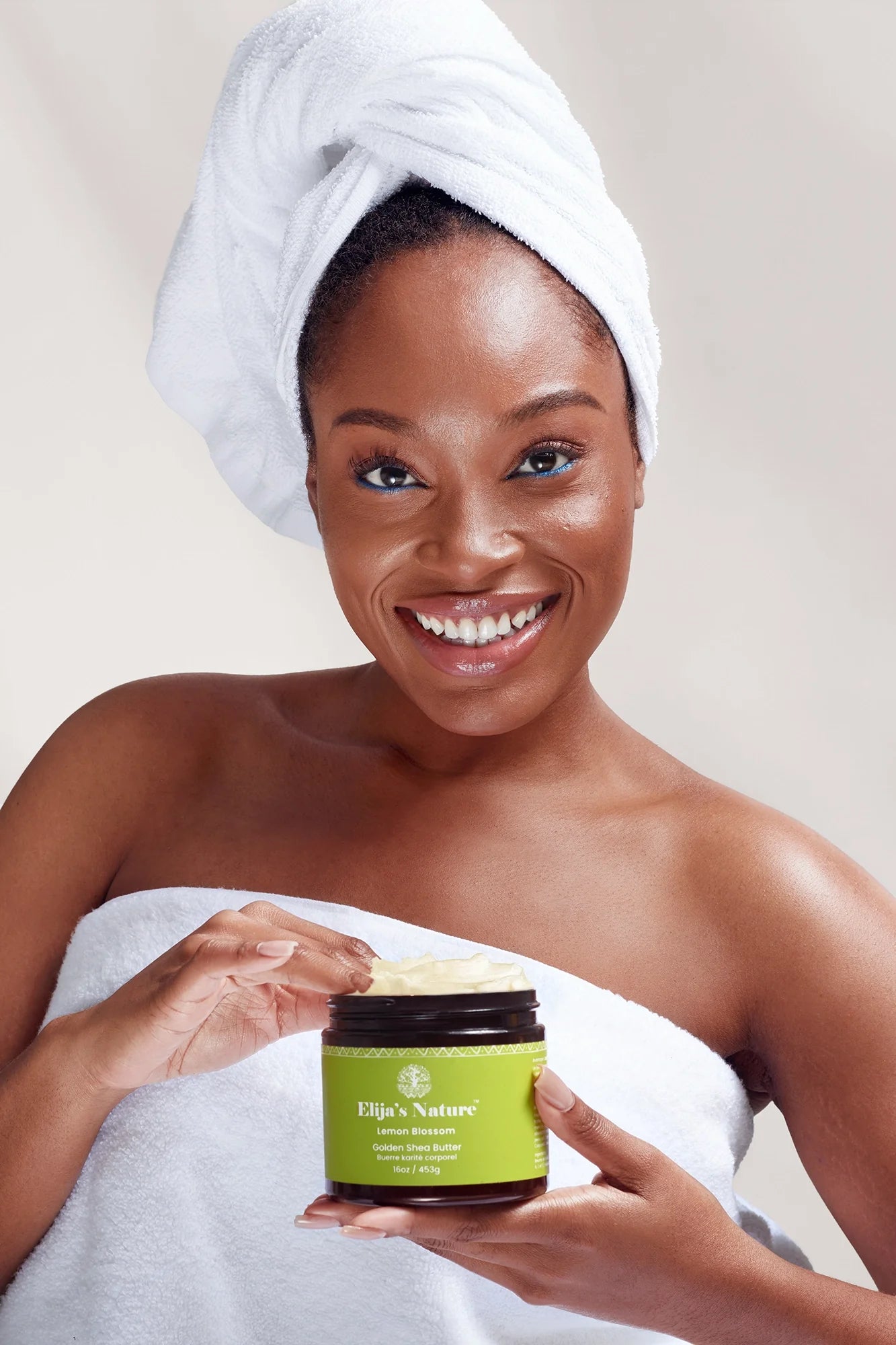 Golden Body Butter - #scent_Lemon Blossom #size_16oz - Smiling woman with a towel wrapped around her head and body, holding a jar of Golden Body Butter while smiling