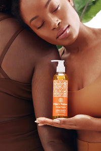 Golden Body Oil - #scent_Mango Papaya #size_8oz – A serene woman leans against her friend while holding a bottle of Golden Beauty Oil in Mango Papaya