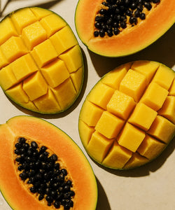 #scent_Mango Papaya - Halved papayas and mangoes, with papayas showing black seeds and mangoes cubed, arranged on a light background