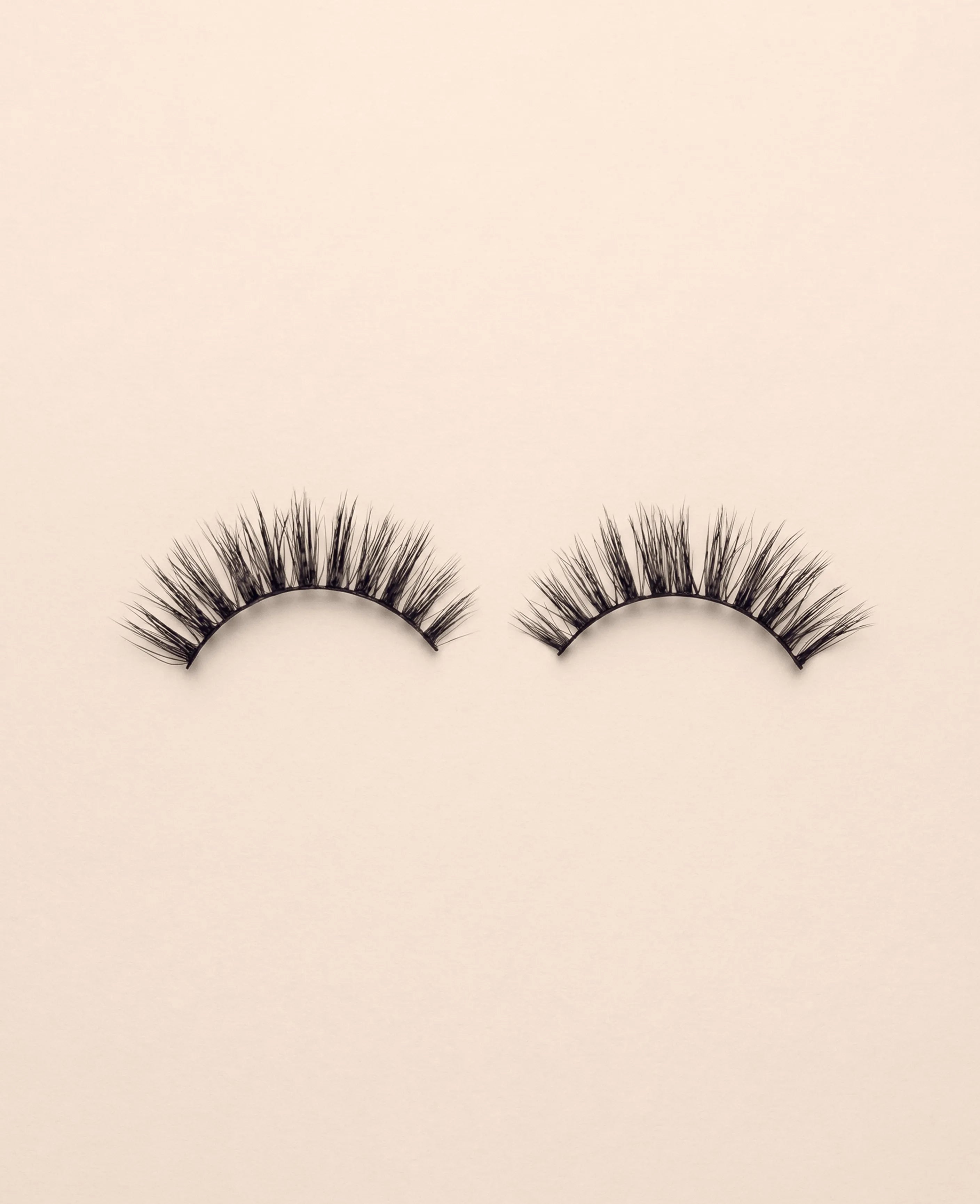 Pair of Media false eyelashes on a beige background.