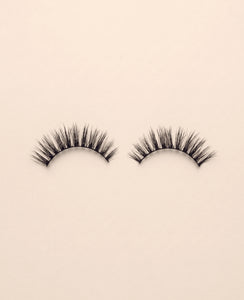 Pair of Media false eyelashes on a beige background.