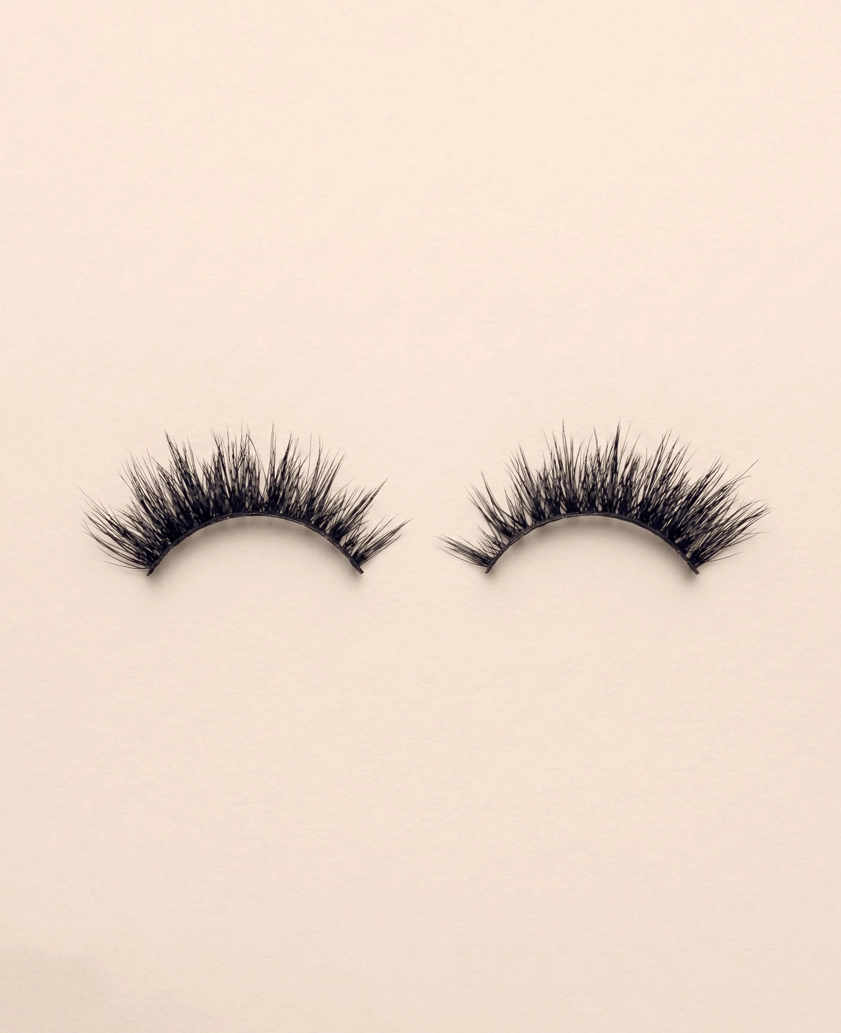 Pair of Nova false eyelashes on a beige background.