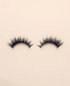 Pair of Nova false eyelashes on a beige background.