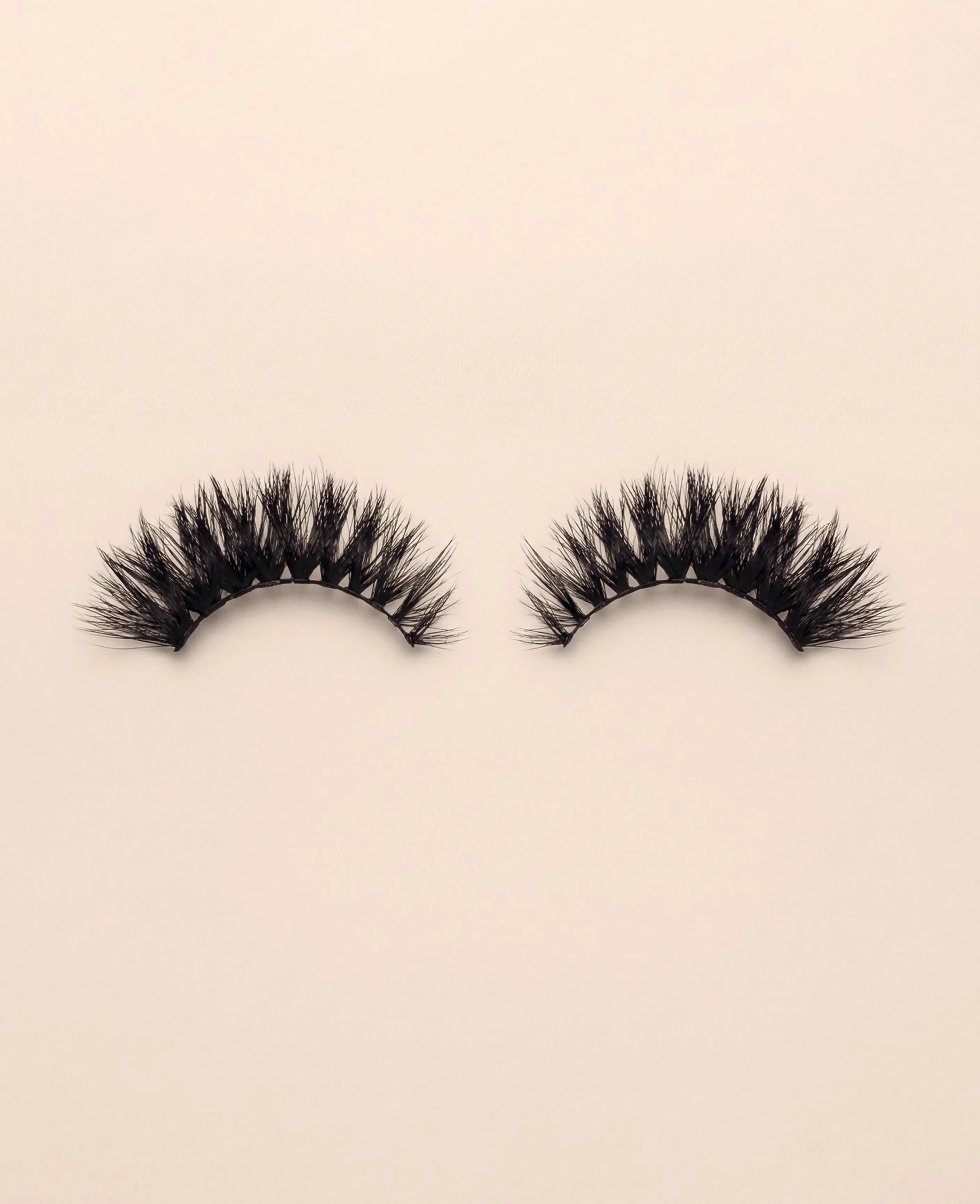 Pair of Strobe false eyelashes on a beige background.