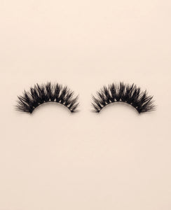 Pair of Strobe false eyelashes on a beige background.