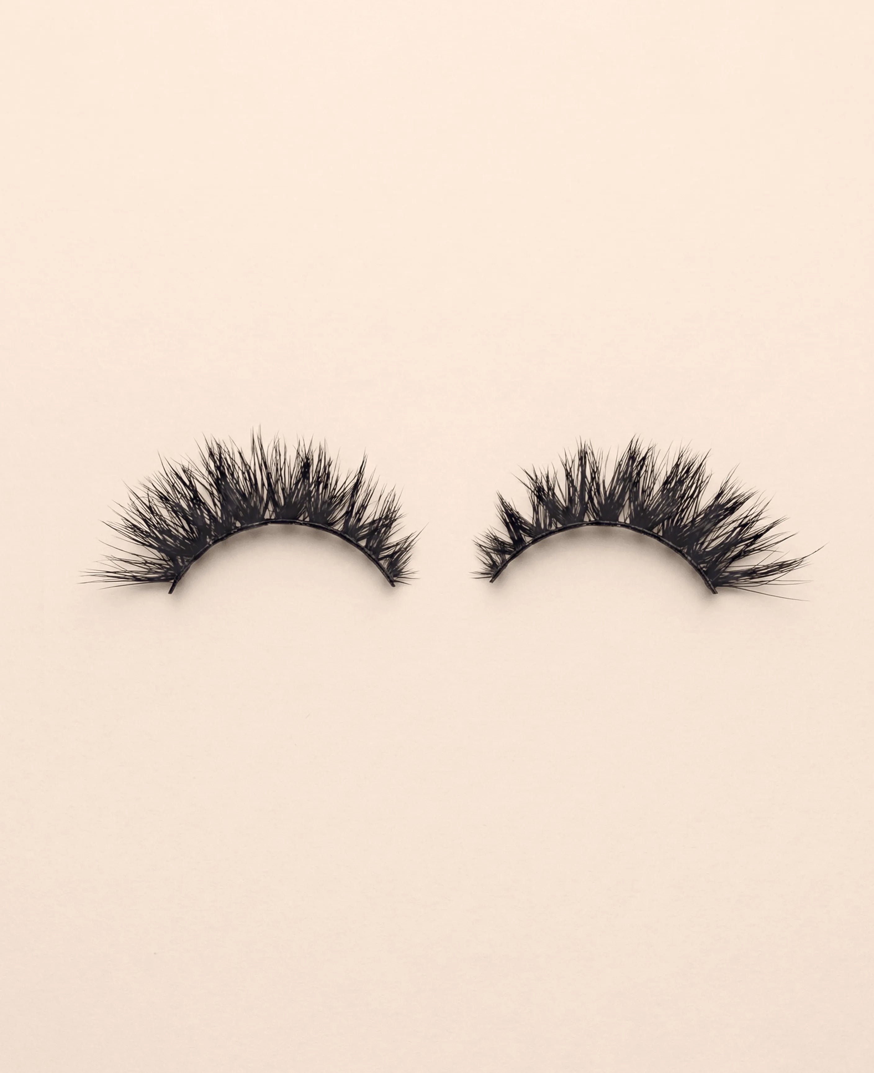 Pair of Supermodel false eyelashes on a beige background.