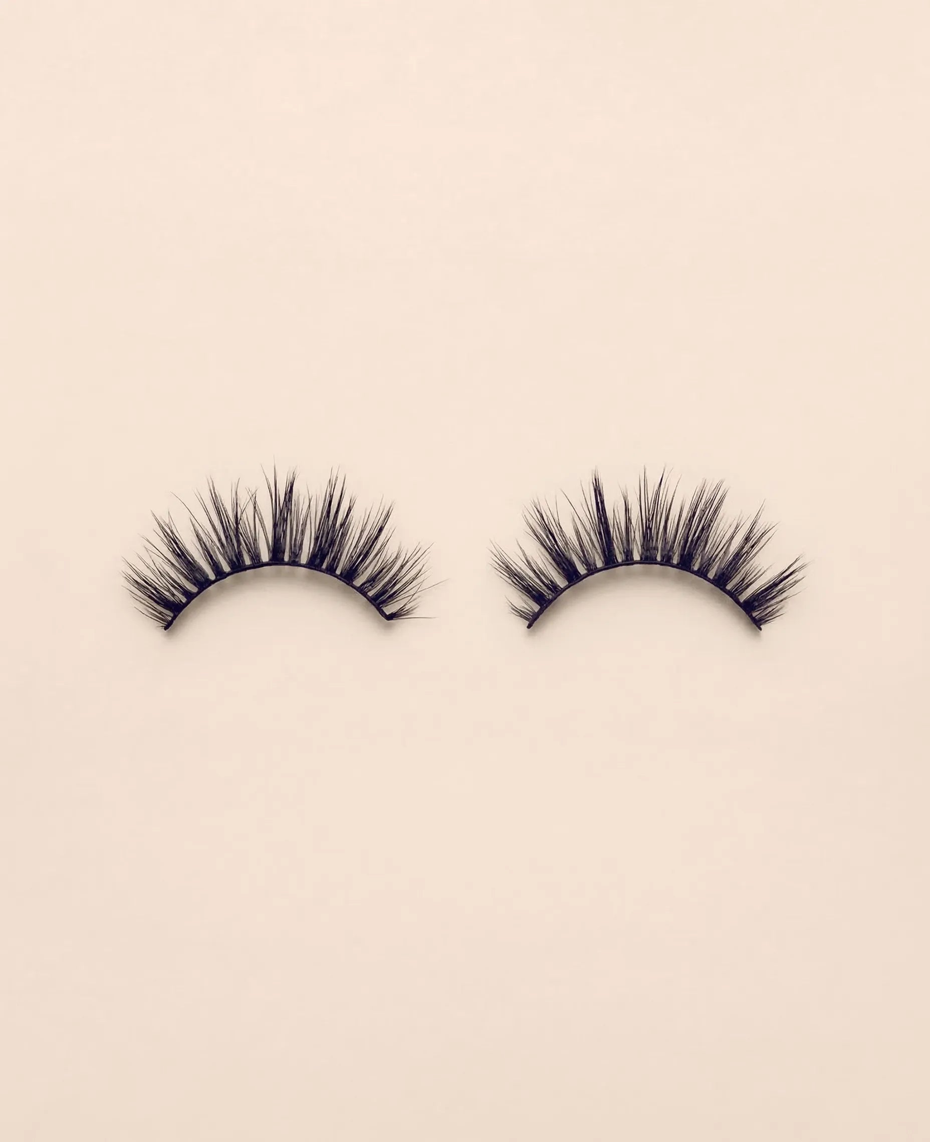 Pair of Sweetie false eyelashes on a beige background.
