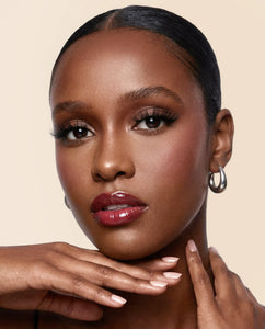 Close-up of a woman wearing Sweetie false lashes on a neutral background.