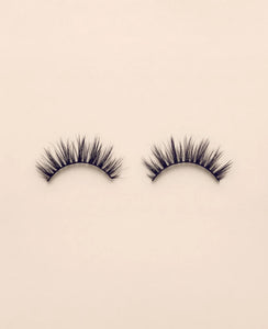 Pair of Sweetie false eyelashes on a beige background.